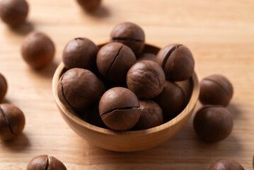 Macadamia nuts in bowl on wooden background