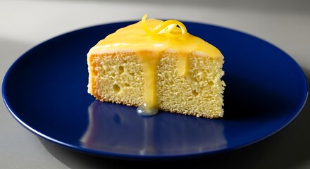 A delicious slice of lemon drizzle cake with yellow icing and zest on a vibrant blue plate.