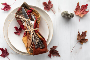 Fall inspired table setting with a colourful cloth napkin tied in raphia.