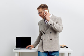 young caucasian man working laptop smartphone talking on phone office digital nomad remote work technology concept