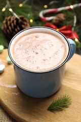 Tasty hot cocoa drink in mug and Christmas decor on table, closeup