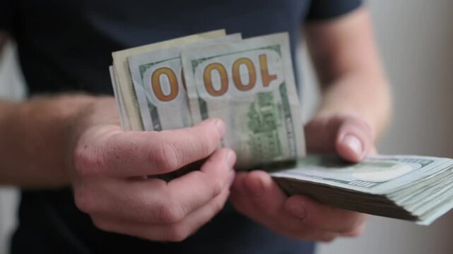 casual worker counts currency after shift, service employee counts all tips and earnings in dim light, routine service worker totals small dollar bills and tips in lowlit indoor environment