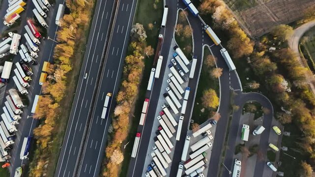 moving trucks on busy road, aerial perspective of bustling highway with parked and moving trucks, overhead view capturing congested highway active with freight trucks and roadside facilities