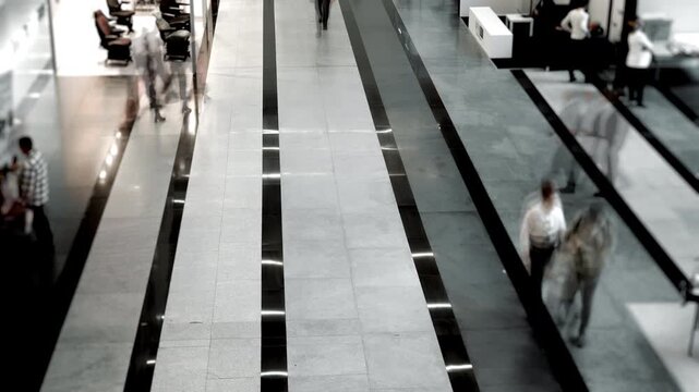 Abstract timelapse of blurred people walking through bright modern hall indoors suitable as concept for shopping mall metro airport or railway station traffic.