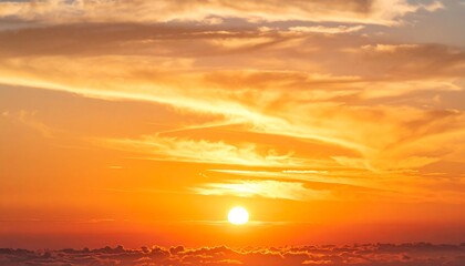Vivid orange and yellow sunset with fluffy clouds and a bright sun