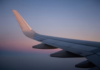Obraz premium Sleek airplane wing silhouette against a vibrant twilight sky during high altitude flight.