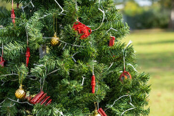 A lush green artificial fir Christmas tree with clear mini lights strung around the festive decoration. There are multiple red painted metal plumbing supplies hanging on the thick branches. The decora