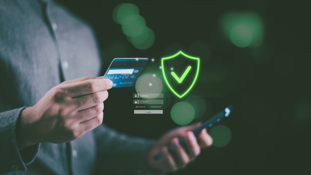 A person holding a credit card and smartphone with a glowing shield icon, representing secure online payment, data protection, cybersecurity, digital banking, and trusted financial transaction.