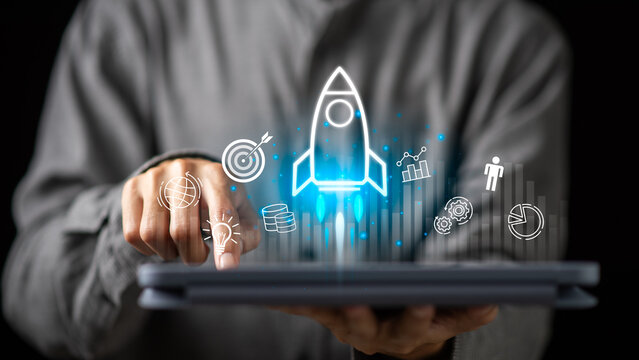 A businessman using a digital tablet with a glowing rocket icon, symbolizing startup innovation, business launch, financial growth, creative technology development for success in modern digital era.