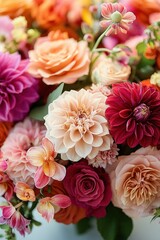 Close-up of a vibrant mixed bouquet of dahlias, roses and orchids in warm pink, peach and red tones conveying romantic joyful elegance
