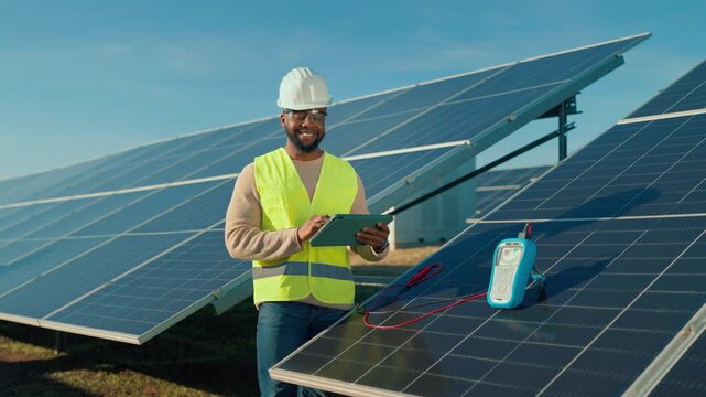 Solar energy technician inspects solar panels at a renewable energy site in clear weather