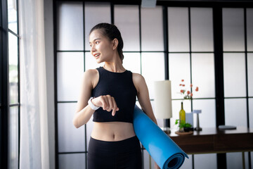 Sporty asian woman in sportswear with health app on smart watch and Yoga mat after training Exercise wellness health sportswoman wellness health rolling Yoga mat after training 