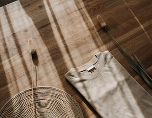 Beige folded t-shirt mockup with pampas grass on wooden floor flatlay