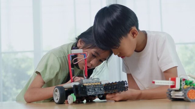 Asian children engineer working on robotics project in a STEM education class. child is focused on assembling and learning about a small robot or electronic project. engineering, innovation, technolog