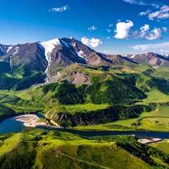 Aerial view of a scenic mountain range with snowy peaks, lush green valleys, and a winding river under a sunny blue sky