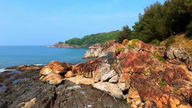 Drone flying low over the rocky coast of Om beach, golden hour in Gokarna, India