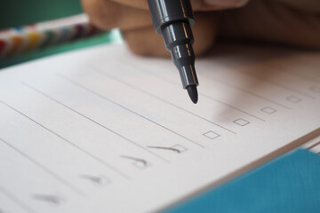 Writing checklist items on lined paper with a marker pen