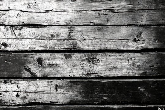 close-up of weathered horizontal wooden planks with knots and cracks in high-contrast black and white conveying a gritty rustic mood