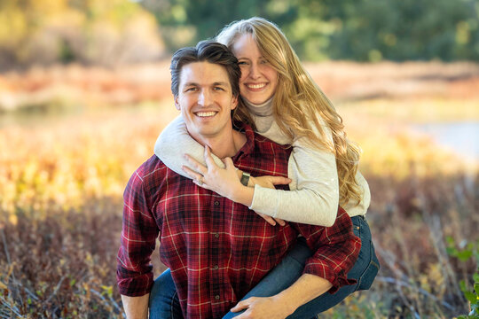 joyful couple in nature, romantic friends laughing together outdoors during sunset in fall scenery - Powered by Adobe