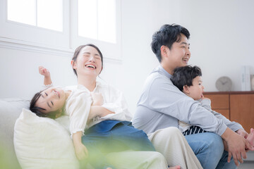 Fototapeta premium ソファで笑い合う家族団欒と幸せの瞬間 大笑いでわちゃわちゃ家族