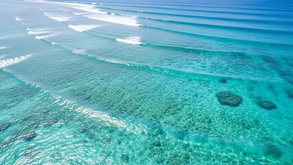 Aerial View of Clear Blue Ocean Waves Rolling Over Coral Reef in Sunny Tropical Setting