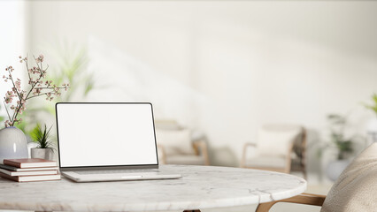 White screen laptop with book and sakura cherry blossom flower vase on round marble table and armchair.
