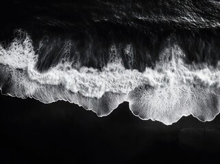 Aerial black and white view of crashing ocean waves and foamy shoreline, a dramatic moody high-contrast seascape of motion and power
