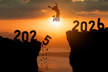Person jumps over a gap between two cliffs representing year transition from 2025 to 2026, capturing a moment of hope and adventure at sunset