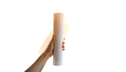 Hand holding a rolled cylindrical object with a flat sheet against a black backdrop