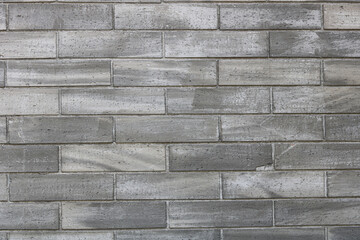 A full-frame shot of a gray and white brick wall, showing the irregular texture and color variations of the individual bricks.