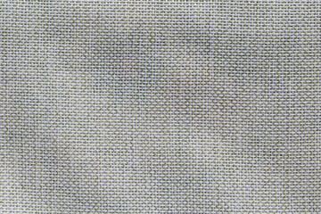 A closeup, full-frame shot of a natural linen or hessian fabric with a distinct basketweave pattern, showing the intricate texture and weave.