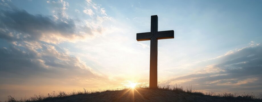 wooden cross silhouette on a grassy hill at sunrise with sunburst and dramatic cloudy sky, evoking peaceful, solemn, hopeful and reverent mood - Powered by Adobe