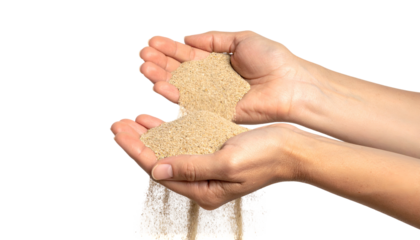 Two hands holding sand, with granules flowing out against a black background