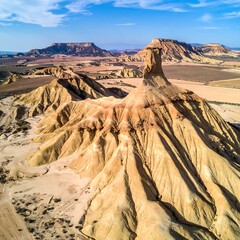Aerial view of a desert landscape with unique rock formations, under a blue sky with wispy clouds