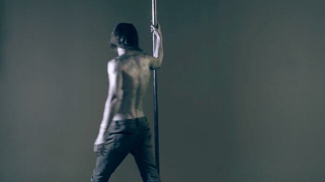 A guy with a naked torso and a gray body art walks around the pylon. Body art concept.