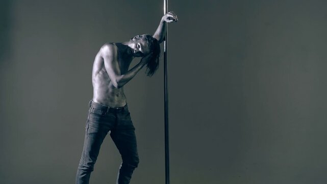 Sexy man pole dancer. Guy does gymnastic exercises on pole dance. Pole dancing for slim fitness body. Flexibility. Pole dance. Pylon dancing strength, flexibility, and grace. Strip dancer.