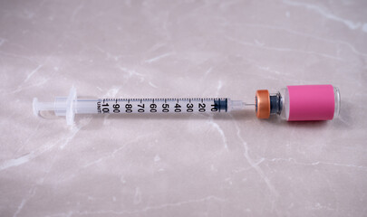 Single Use Syringe Next to Small Glass Vial