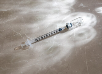 Single Use Syringe Next to Small Glass Vial