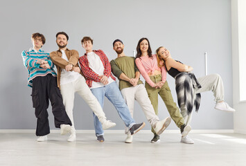 Friendly dancing group of young happy funny people actively fun dancing indoors, moving together with trainer, participating in team class or rehearsal, learning performing steps, enjoying, exercising