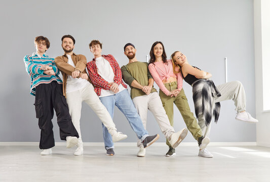 Friendly dancing group of young happy funny people actively fun dancing indoors, moving together with trainer, participating in team class or rehearsal, learning performing steps, enjoying, exercising