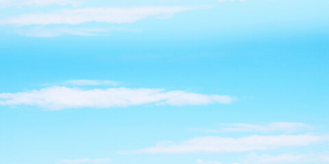 Serene and minimalist soft pale light blue sky with distinct white wispy clouds floating. Sky background uniform and has subtle clean gradient suggesting clear day