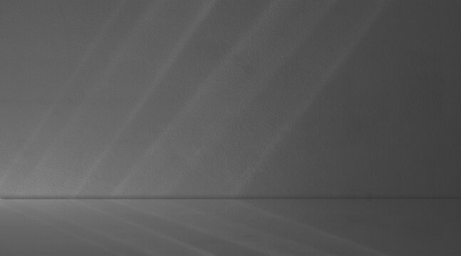 Dark gray monochromatic corner empty room concrete. Diagonal bands of bright, natural light fall across surfaces from upper left, creating striking parallel highlights and shadow