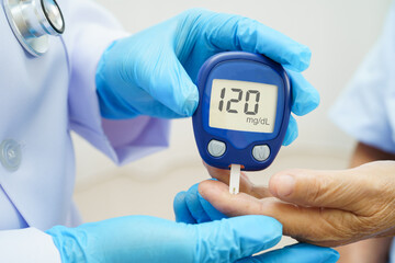 Asian doctor using digital glucose meter for check sample blood sugar level to treatment diabetes.