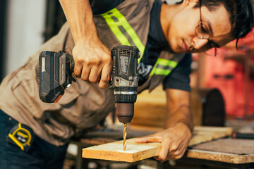Cabinetmaker working on a piece of furniture with a drill in the carpentry shop. Close-up of a construction man using a drill
