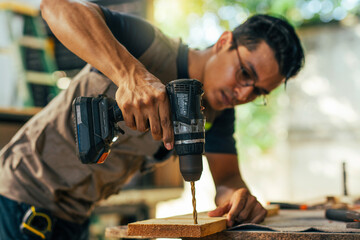 Close-up of a construction man using a drill. Cabinetmaker working on a piece of furniture with a drill in the carpentry shop