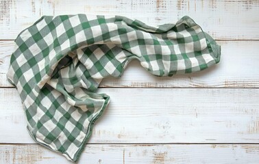 green and white checkered tea towel casually draped on a white distressed wooden table, evoking cozy farmhouse kitchen comfort