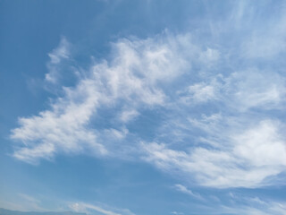 Soft, wispy clouds stretch across a bright blue sky, creating a calm and airy atmosphere. The light cloud patterns add a peaceful and natural feel, perfect for backgrounds or serene nature themes.

