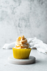 yellow cupcake with orange buttercream frosting on white background, tall buttercream frosting on yellow cupcakes