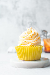 yellow cupcake with orange buttercream frosting on white background, tall buttercream frosting on yellow cupcakes
