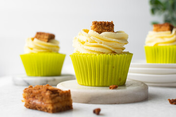 green cupcake with buttercream frosting and a sponge cake garnish on white background, tall buttercream frosting on green cupcakes